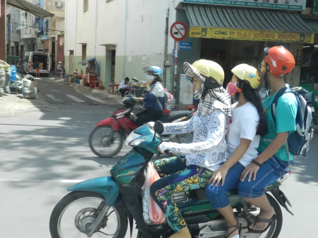 Tre passeggeri, un solo scooter, caschi colorati