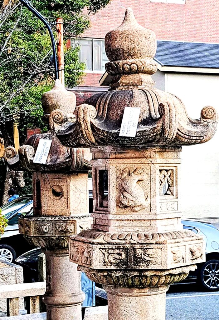 Una delle lanterne di pietra lungo i vialetti di Ikuta Jinja, con un coniglio scolpito nel riquadro laterale.