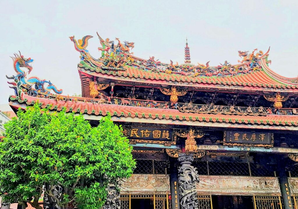 La facciata del Longshan Temple vista dal cortile, con l'antico albero che ne protegge la soglia